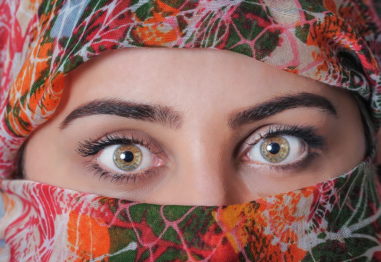 Close-up of a woman’s eyes and neatly shaped brows above a patterned scarf