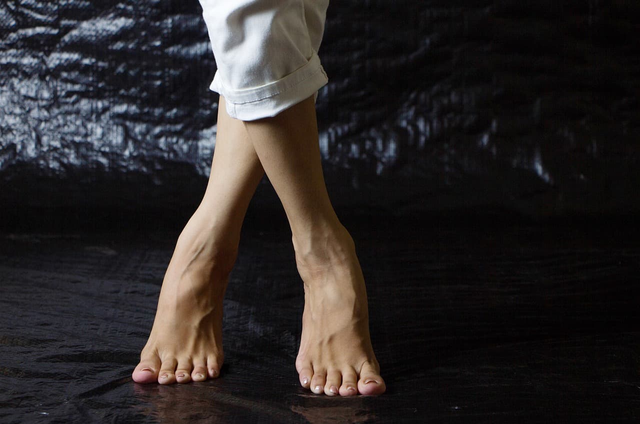 Smooth bare legs, crossed at the ankle, on a dark background